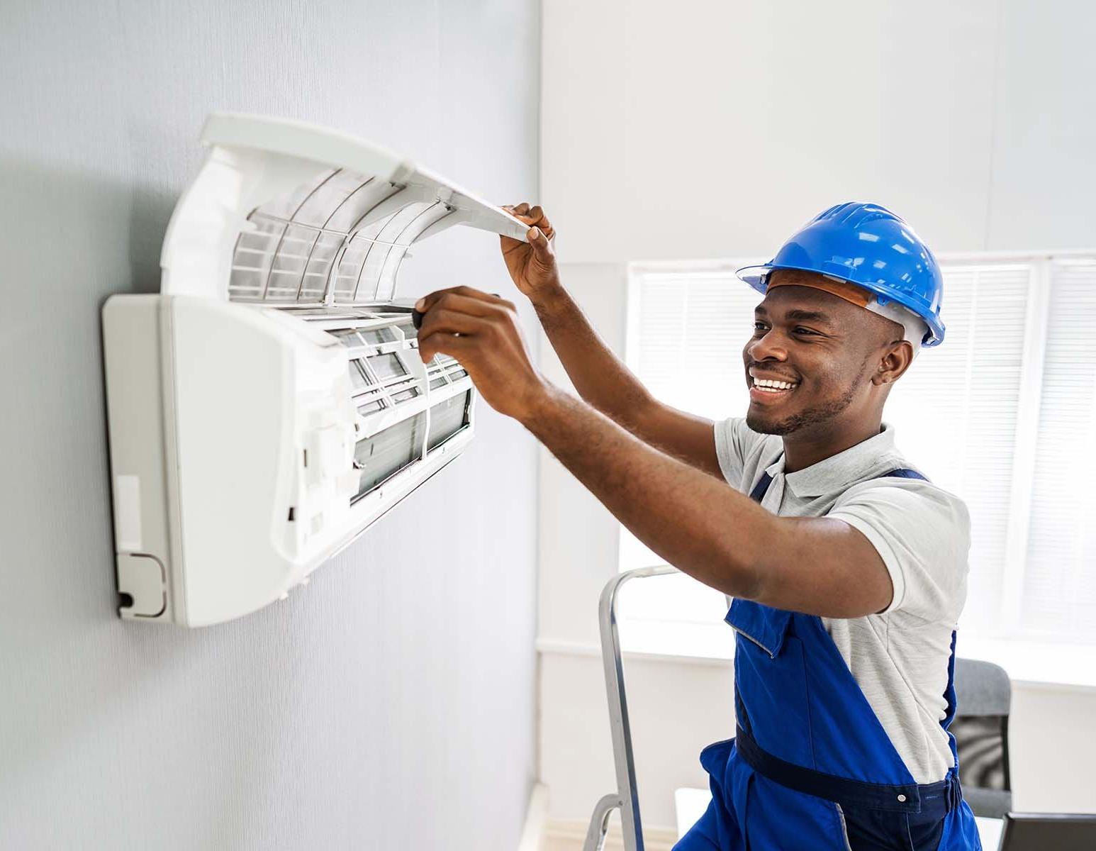 Smiling technician repairing an air conditioner.